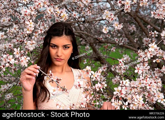 Attractive young beautiful lady, dressed in pink clothing, enjoying the plum blossom flowers. Concept of welcoming Spring