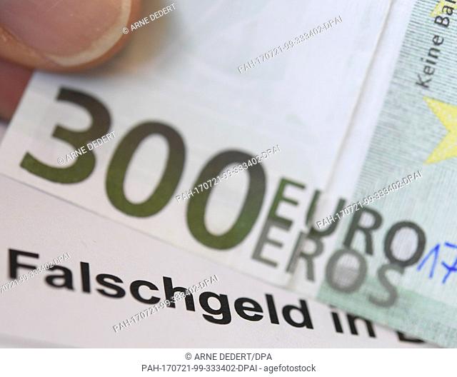 ILLUSTRATION - A counterfeit 300 euro note being held above the caption ""counterfeit money"" at the German Bundesbank headquarters in Frankfurt am Main
