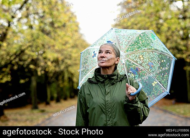 Thoughtful senior woman holding umbrella