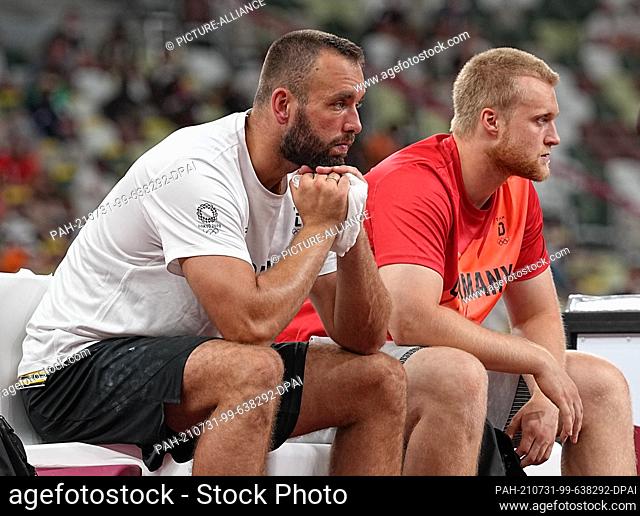 31 July 2021, Japan, Tokio: Athletics: Olympics, discus throw, men, final at the Olympic Stadium. Germany's Daniel Jasinski and Clemens Prüfer (r) sit together...