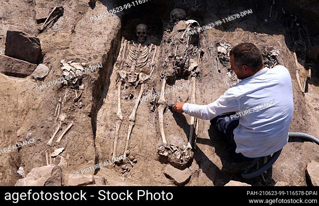 23 June 2021, Saxony-Anhalt, Eisleben: Archaeologist Normen Posselt uncovers a grave at an excavation site near Helfta near Eisleben