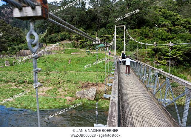 New Zealand, North Island, Waikato, Karangahake Gorge, family crossing suspension bridge