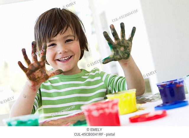 Smiling boy finger painting indoors
