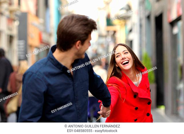 Happy couple running together in the street in winter