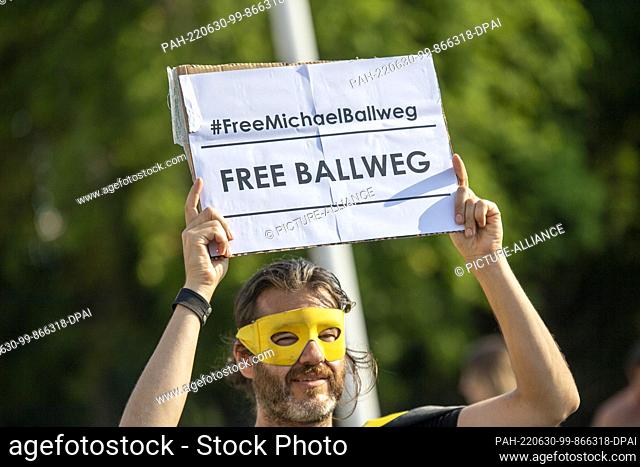 30 June 2022, Berlin: Michael Bründel aka Captain Future holds a placard reading ""#FreeMichaelBallweg - Free Ballweg"" at a rally in front of the Brandenburg...