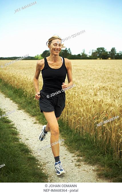 Woman jogging in an open landscape, Sweden