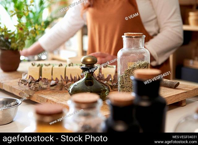Woman decorating organic soap with rosemary leaves at workshop