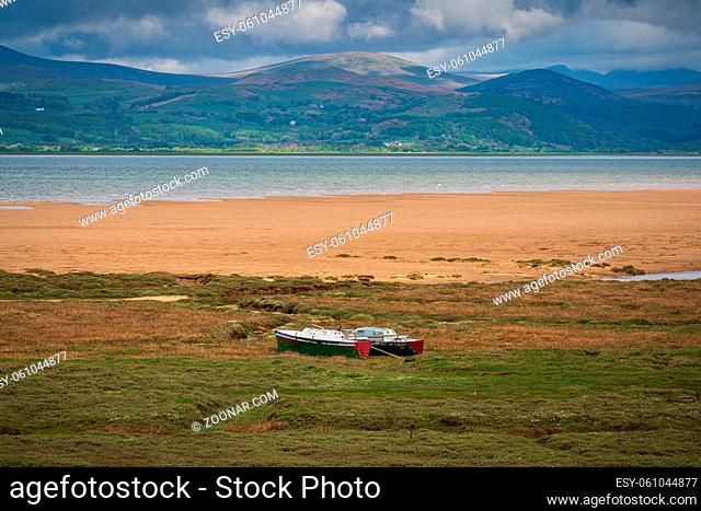 Boats in the grass, with clouds over the Lake District National Park in the background, seen in Askam-in-Furness, Cumbria, England, UK
