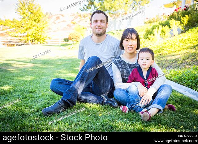 Happy mixed-race family having fun outside on the grass