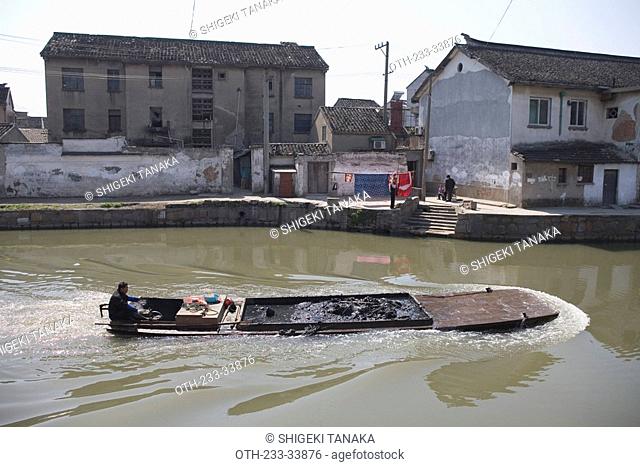 A sampan in the canal Folk houses alongside, Suzhou, China