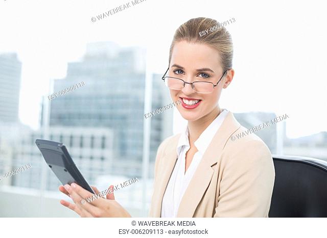 Cheerful businesswoman with glasses using calculator