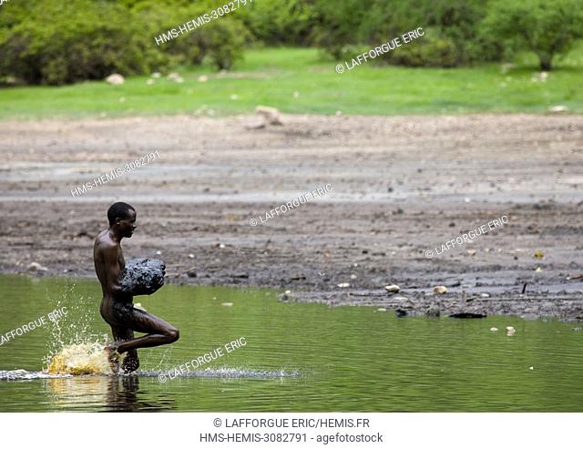 Ethiopia, Oromia, El Sod, Borana tribe man getting out of the crater lake of el sod volcano with volcanic mud in the arms