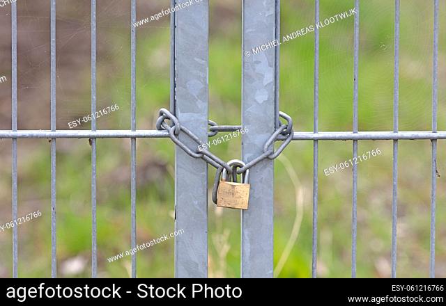 Large metal fence locked with a padlock and a chain, selective focus