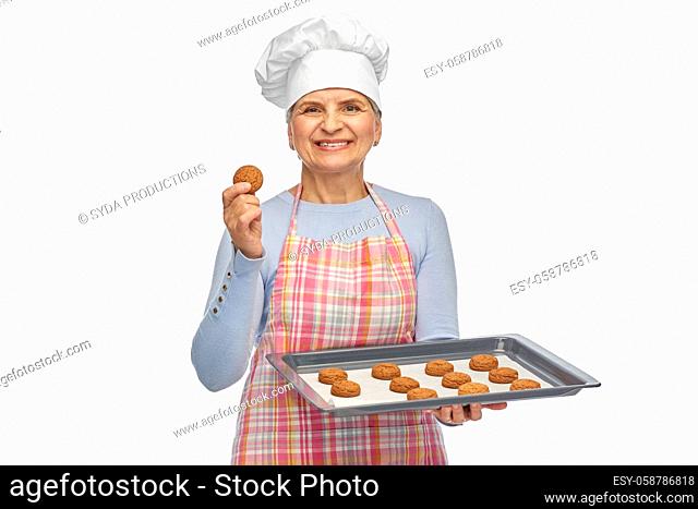 senior woman in toque with cookies on baking pan