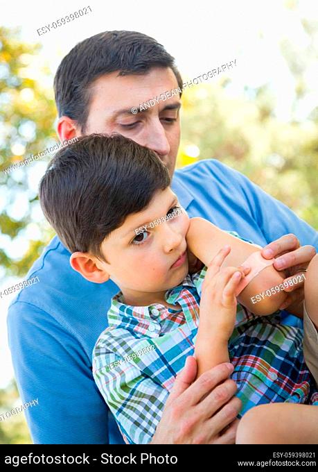 Loving Father Puts a Bandage on the Elbow of His Young Son in the Park