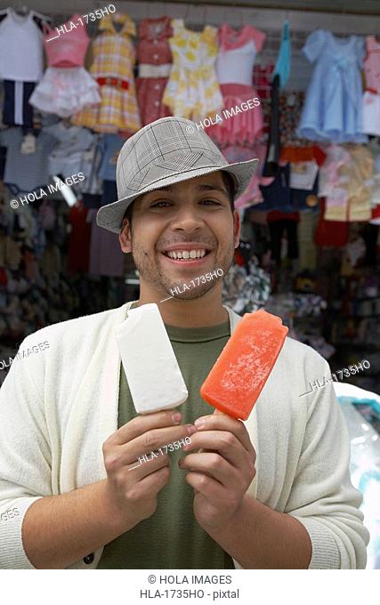 Portrait of a young man offering two ice creams