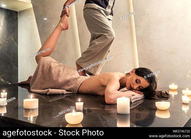 Young woman lying down while enjoying the stretching techniques of a professional Thai massage in luxury spa and wellness center