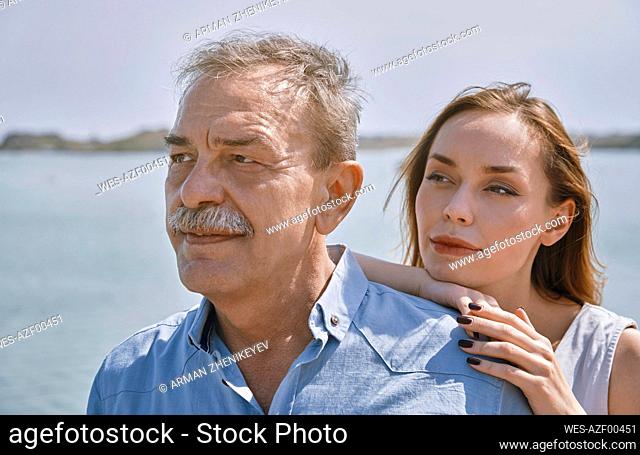 Thoughtful young woman standing with father next to sea