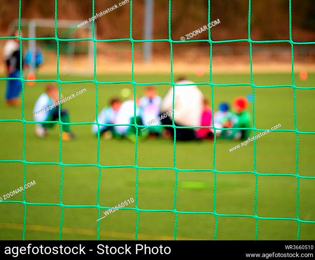 Football gate net. Soccer gate net. In blurry background stand players. Training of junior team