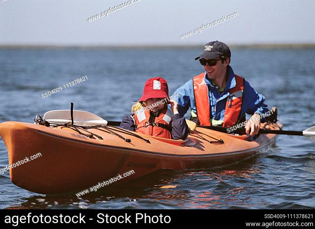 Father and young daughter in kayak wearing life-jackets