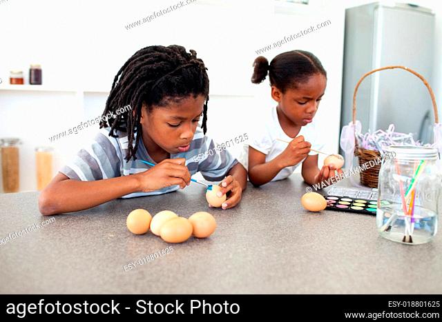 Concentrated Afro-american siblings painting eggs
