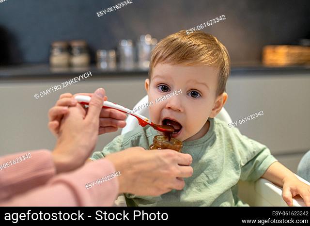Feeding a baby. Parents feeding a cute baby boy in the kitchen