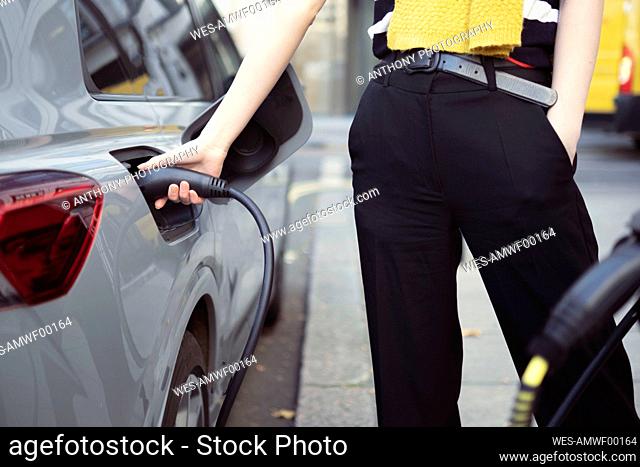 Woman charging electric car at charging station