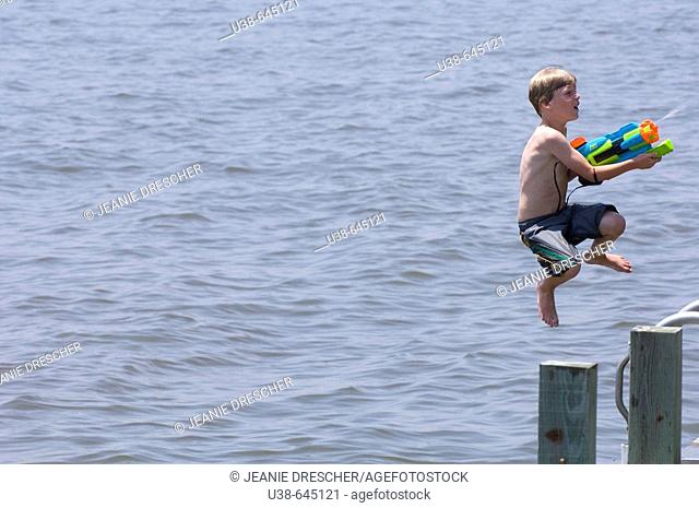 boy shooting water gun while jumping into the Albemarle Sound, North Carolina