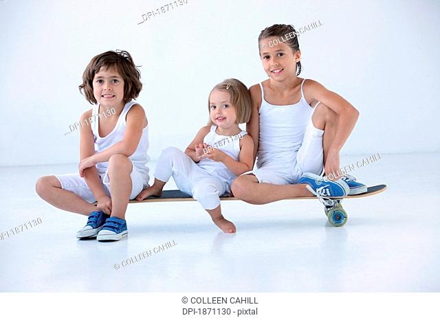 three young girls sitting on a longboard