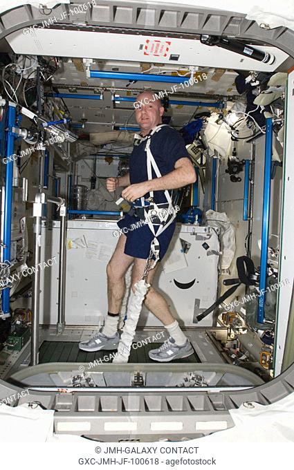 European Space Agency astronaut Andre Kuipers, Expedition 30 flight engineer, equipped with a bungee harness, exercises on the Combined Operational Load Bearing...