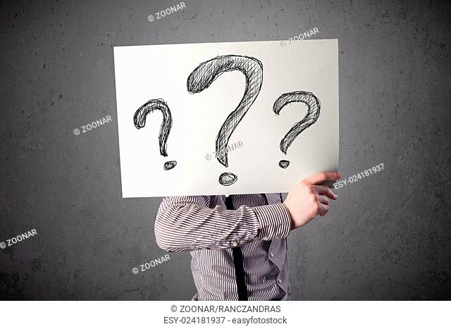 Businessman holding a paper with question marks in front of his head