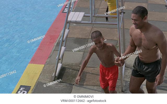 Father and son walking hand in hand and jumpping to pool