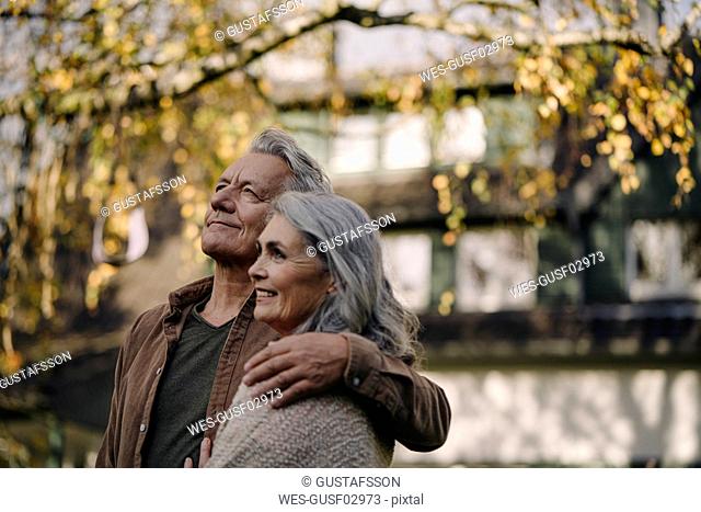 Affectionate senior couple in garden of their home in autumn