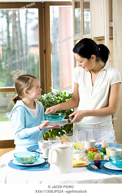 Daughter helping mother with preparing breakfast