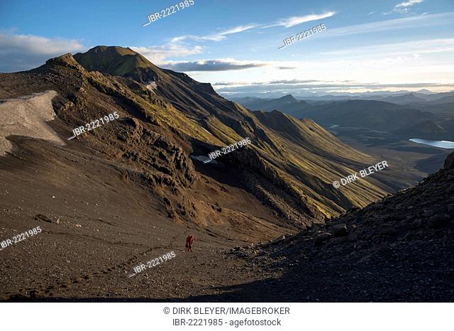 Hiker climbing Sveinstindur Mountain, overlooking Lake Langisjór, Highland, Iceland, Europe