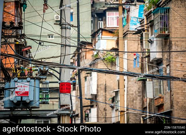 Yichang, China - August 2019 : Densely wired telephone and electric cables outside residential buildings in Yichang town