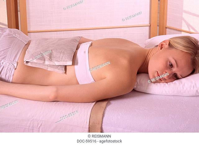 Woman treating her back with an hayflowers back against muscle pains