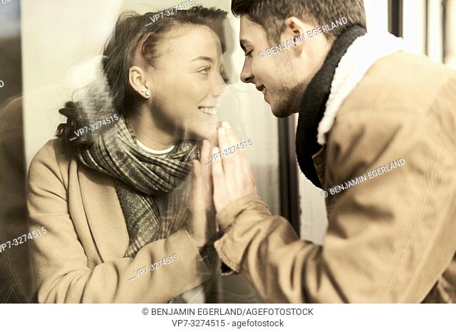 young teenage lovers separated by window, trying to touch hands, in Cottbus, Brandenburg, Germany