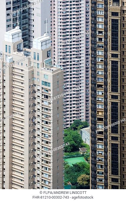 View of small garden and tennis court amongst skyscraper apartment blocks in densely populated area of city, Hong Kong, China