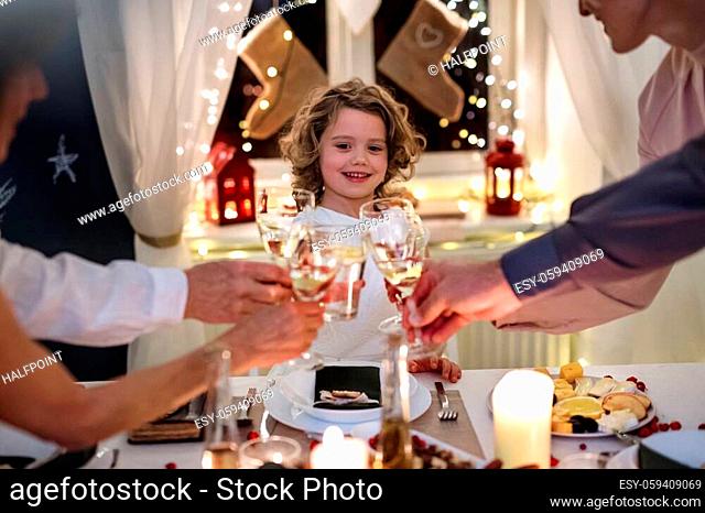 Unrecognizable multi-generation family indoors celebrating Christmas together, clinking glasses