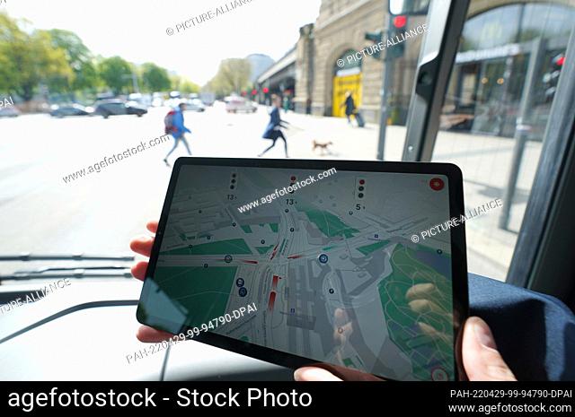 29 April 2022, Hamburg: An employee holds a tablet with an information app about the traffic situation on a bus on the test track for automated and connected...