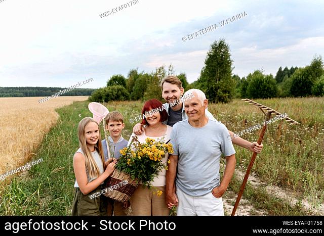 Happy family with flowers and rake at field