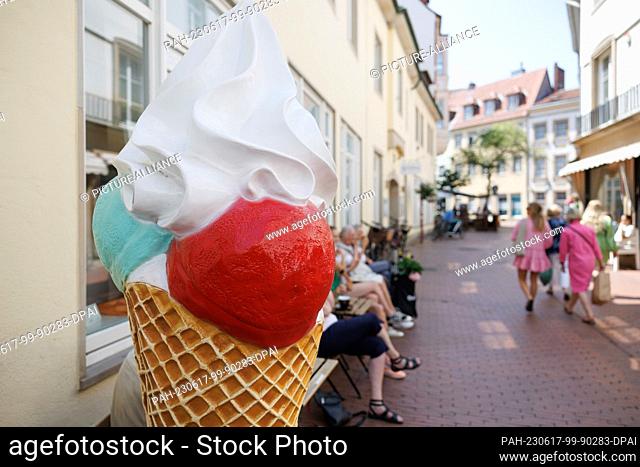 17 June 2023, Lower Saxony, Osnabrück: An exhibitor in the shape of a giant ice cream cone stands in front of an ice cream parlor