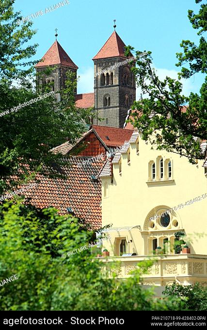 18 July 2021, Saxony-Anhalt, Quedlinburg: The towers of the collegiate church jut out behind residential buildings. In the historic old town with its...
