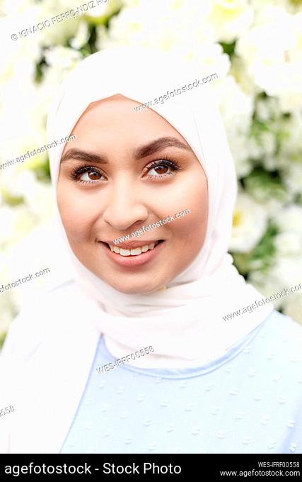 Happy woman looking away in front of white flowers decoration
