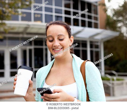 Caucasian student using cell phone on campus