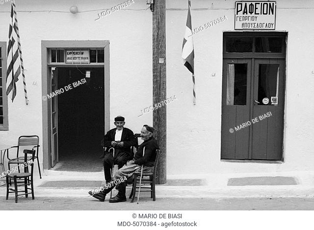 Two old men sitting in the street in a Greek island. Greece, 1970s