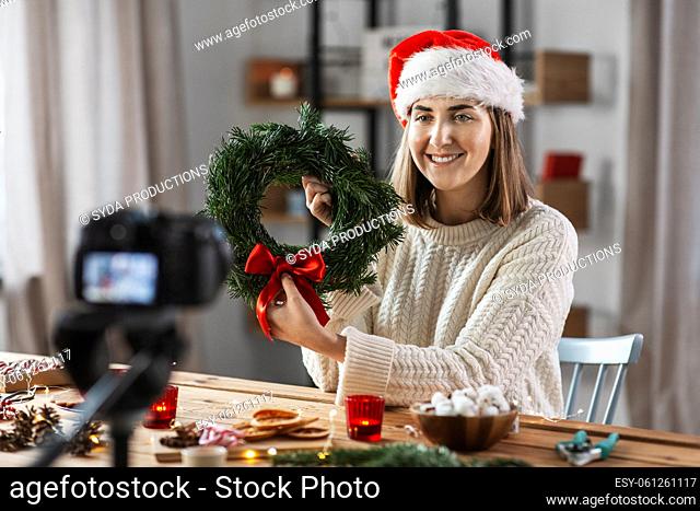 woman with camera and fir christmas wreath at home