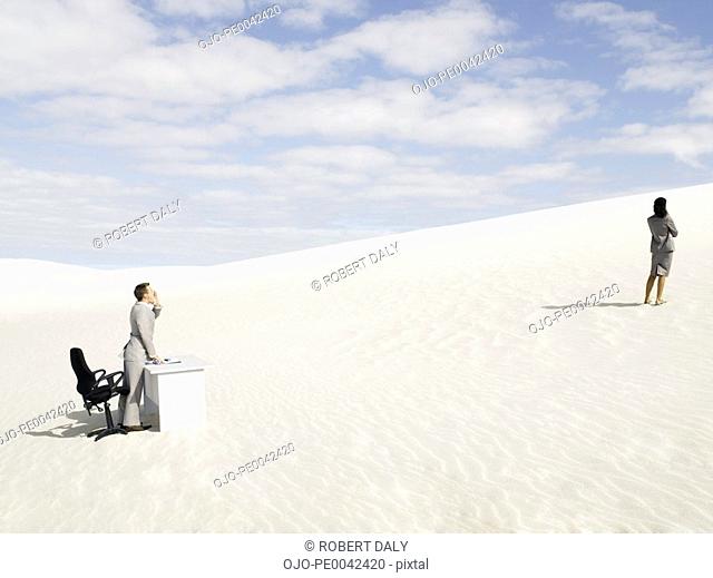 A businessman yelling to a businesswoman in the middle of nowhere
