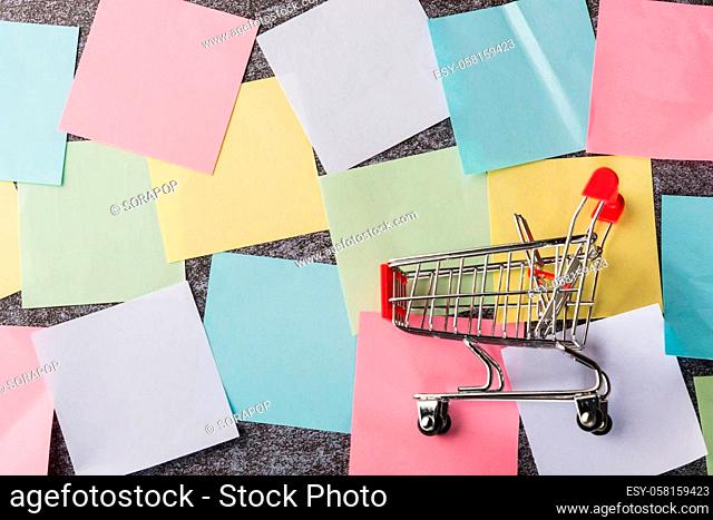 Above many blank paper stick note list with the shopping cart on concrete board, Shopping reminder memory today concept
